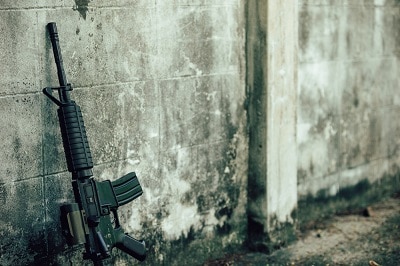 Assault rifle gun for the American military is placed beside the old wall.